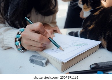 close up unrecognizable Woman making a sketch at home she is using graphite pencil and writing on white sheet, there is an eraser on the table, studio concept, copy space - Powered by Shutterstock