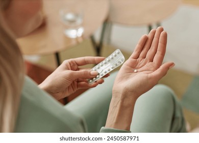 Close up of unrecognizable woman taking birth control pill at home in open hand copy space - Powered by Shutterstock