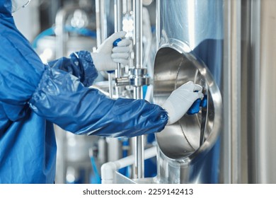 Close up of unrecognizable worker wearing protective gear while operating equipment at chemical factory and opening vault - Powered by Shutterstock