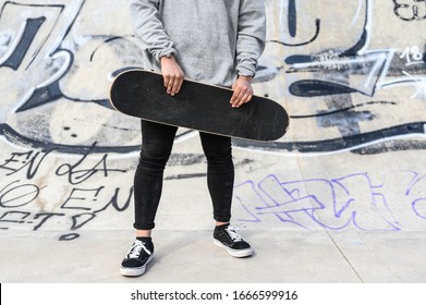 Close up of unrecognizable young man holding longboard or skateboard in the park . - Powered by Shutterstock