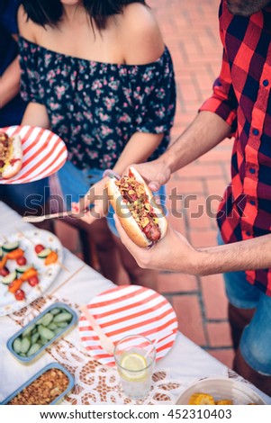 Mann hält Hot Dog im Barbecue mit Freunden.