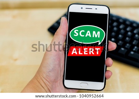 Close uo image of hand holding a smartphone with black screen and text scam alert. Internet issue and viral. Shallow DOF, selective focus.