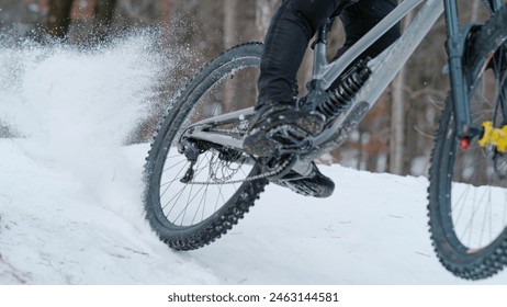 CLOSE UP: Adrenaline winter mountain bike riding on snow-covered forest trail. Mountain biker sprays snow while racing down the snowy mtb trail. Action bike ride in the woods after fresh snowfall. - Powered by Shutterstock