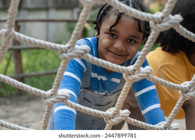 Close up, African child boy climbing a rope ladder and smile at the camera - Powered by Shutterstock