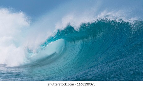 CLOSE UP: Beautiful deep blue tube wave in the wild Pacific Ocean curls towards a remote tropical island on a sunny day in summer. Spectacular shot of wild barrel wave coming from the exotic sea.