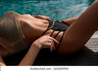 CLOSE UP: Beautiful model body in a black and gold bikini relaxes near the pool. Beach Fashion Summer Clothing
