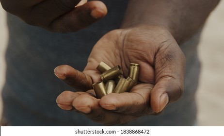 Close Up, Black Man Hands Counting Used Bullets. Many Bullet Cases Transfered From One Hand To Another. High Quality Photo