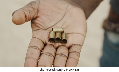 Close Up, Black Man Hands Counting Used Bullets. Many Bullet Cases Transfered From One Hand To Another. High Quality Photo