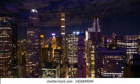 CLOSE UP: Breathtaking view of countless skyscrapers of New York lit up at night. Picturesque view from above of glassy high rise office buildings in a bustling metropolitan city in the night-time.