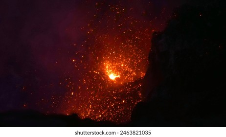 CLOSE UP: Bright lava exploding from the depths of Mount Yasur lighting up the crater. Breathtaking shot of dangerous glowing lava being blasted out of an active crater in Sicily. Volcano erupting.