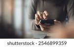 Close up, business woman using mobile phone with laptop computer on office table. Woman using smartphone for online shopping and digital banking via mobile app, social media marketing