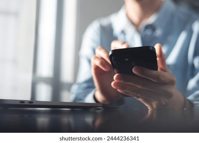 Close up, business woman using mobile smart phone searching the information, surfing the internet during working on laptop computer at office, social media marketing - Powered by Shutterstock