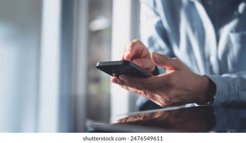 Close up, business woman using mobile smart phone on glass table with reflection and sunlight. Woman using smartphone during working at office with digital tablet on table, social network