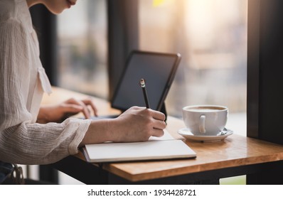 Photo of Close up. Businesswoman hand taking notes working at a café.
