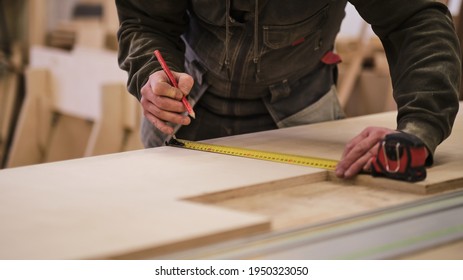 Close up. Carpenter holding a measure tape on the work bench. Woodwork and furniture making concept. Carpenter in the workshop marks out and assembles parts of the furniture cabinet