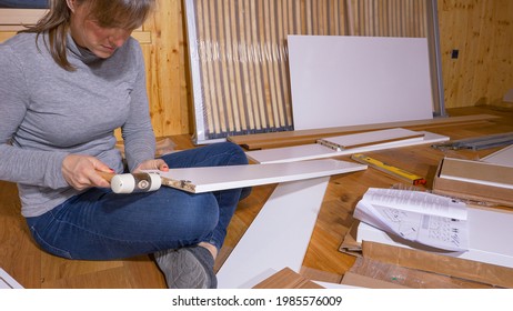 CLOSE UP: Caucasian Female Hammers Small Wooden Pegs Into A Plywood Board As She Assembles A Closet. Unrecognizable Young Woman Uses A Soft Faced Mallet While Assembling Furniture In Her Bedroom