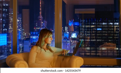 CLOSE UP: Caucasian Woman On A Business Trip Sits In Her Hotel Room With A Spectacular View Of NYC At Night And Works On Her Computer. Student Working On Her Project From Hotel Room Above Times Square