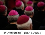 close -up of clerics in the amaranth zucchetto (form-fitting ecclesiastical skullcap) praying during the mass in the chapel