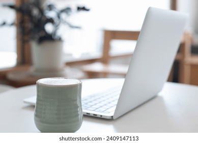 Close up, cup of coffee and laptop computer on white table in coffee shop with no people, copy space for business background, freelance lifestyle - Powered by Shutterstock