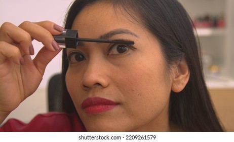 CLOSE UP: Detailed View Of Pretty Philippine Woman Applying Mascara To Eyelashes. Headshot Of Young Lady Putting On Eye Make Up For Special Occasion. Female Person Taking Care Of Her Glamourous Look.