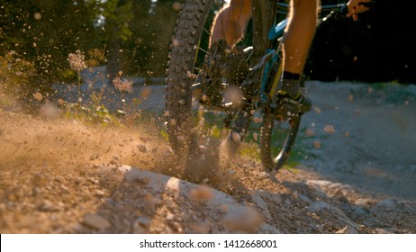 CLOSE UP, DOF: Mountain Biker Kicking Up Dust And Rocks While Braking Hard As He Rides Along The Empty Gravel Trail. Unrecognizable Man Brakes While Riding His Electric Bike Down An Empty Trail.