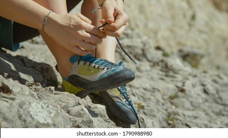 CLOSE UP, DOF: Unrecognizable woman ties her climbing shoes before climbing a difficult boulder. Athletic woman on rock climbing trip gets ready for her first ascent by tying her climbing shoes. - Powered by Shutterstock