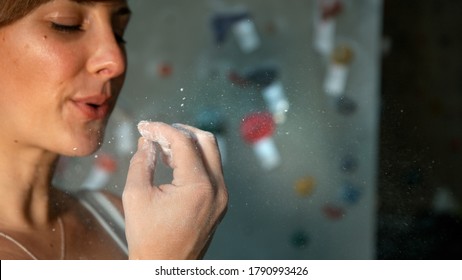 CLOSE UP, DOF: Young Caucasian Woman Blows Excess Magnesium Off Her Fingertips While Climbing In An Indoor Rock Climbing Gym. Female Climber Blows Chalk Off Her Fingertips Before Climbing A Route.