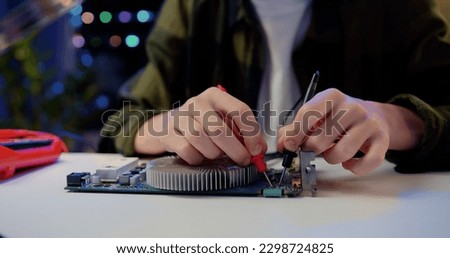 Close Up. Engineer soldering microcircuit. Unknown male hands with a tool repairs a home electronic appliance and screwdriwer on the table at hom.