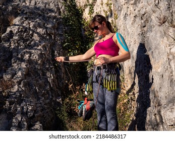 CLOSE UP: Equipped female climber prepares rope for attachment to climbing belt. Preparing climbing equipment for lead climbing up the steep rocky wall. Outdoor sport activity in natural environment.