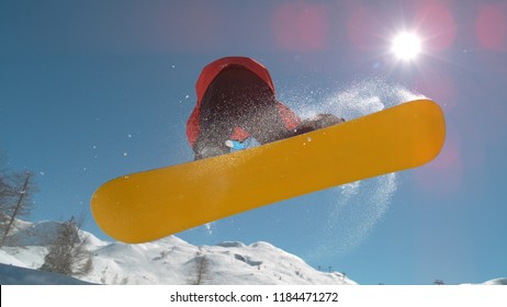 CLOSE UP: Extreme Snowboarder Jumping In Big Mountain Ski Resort. Detail Of Snowboard Taking Off The Kicker In Groomed Snow Park. Snowboarding Jump On Sunny Winter Day In Snb Park