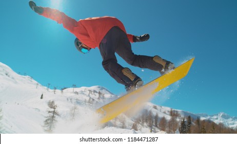 CLOSE UP: Extreme Snowboarder Jumping In Big Mountain Ski Resort. Detail Of Snowboard Taking Off The Kicker In Groomed Snow Park. Snowboarding Jump On Sunny Winter Day In Snb Park