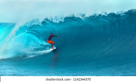 CLOSE UP: Extreme Young Surfboarder Rides A Spectacular Barrel Wave Near A Popular Surf Spot In Stunning Tahiti. Breathtaking Shot Of A Fearless Pro Male Surfer Catching A Huge Deep Blue Tube Wave.