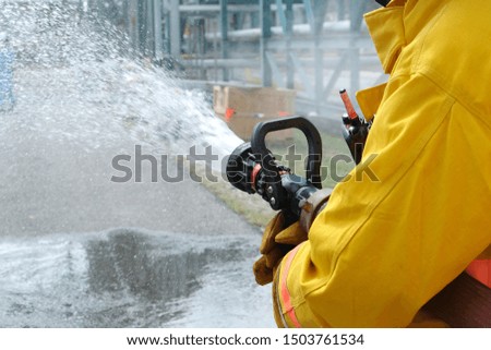 Close up, Firemen use fire hose water spray to the production process as part of emergency drills or emergency drill training at a chemical plant oil and gas factory.