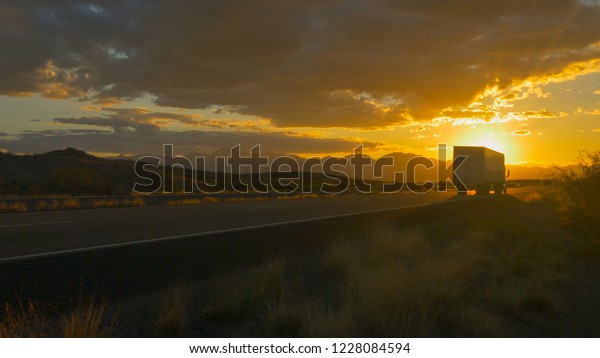 CLOSE UP: Freight semi truck speeding on empty\
highway over golden sun at summer sunset. Transporting truck\
driving on freeway in sunny\
morning.