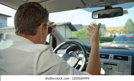 CLOSE UP: Frustrated Caucasian Man Shouts At The Slow Moving Traffic In Front Of Him. Young Male Driver Experiencing Road Rage During His Morning Commute To Work. Irritated Guy Yelling In His Car.