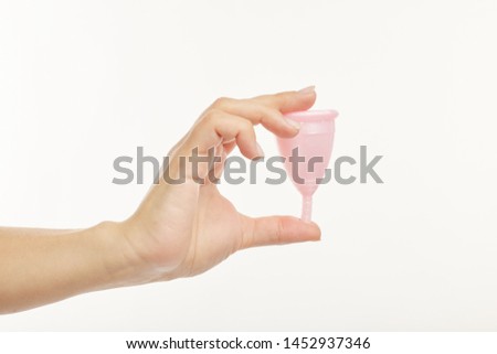 Close up. The girl shows on the menstrual cup on a white background.