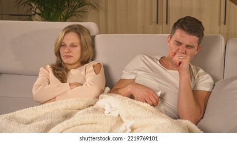 CLOSE UP: Guy Has The Flu And Is Coughing While Watching TV With His Girlfriend. Winter Colds And Flu Spreading Around. Married Couple Cuddling Under Blanket On Comfy Couch While Man Fell Ill With Flu