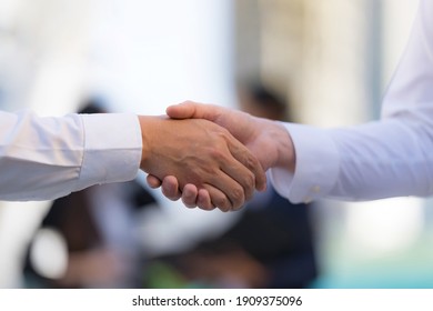 Close up, Handshake of two businessmen on the background of modern office, partnership concept, Shaking hands to seal a deal