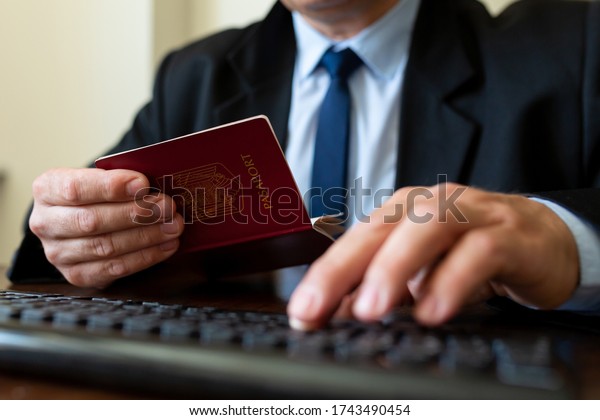 Close up. The immigration control\
officer verifies passport identification\
data.\
