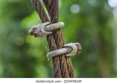 Close up, insulated old rusty steel wire rope and metal wires or ropes connected by old rusty clamps. - Shutterstock ID 2255958149