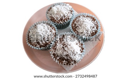 Close up, isolated image of Choc Coconut Muffins with chocolate icing and nutty, desiccated-coconut topping. The taste of a bounty or sweet, tropical, coconut based recipe image. Photo of Chocolate Coconut Cupcakes. Bounty-Style Chocolate-Coconut mini cakes with desiccated or shredded coconut. Small home baked treats in paper wrappers, iced with a rich and indulgent cocoa based icing, then drenched in heavenly white-coconut shreds. Lazy Lamingtons, an easy way to get the taste without all the work, image of alternative to the classic Lamington with all the same flavor profiles.