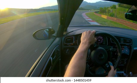 CLOSE UP, LENS FLARE: Man Enjoying A Sunny Day By Driving His Sportscar Along Closed Track. Race Car Driver Speeding Along Empty Track On A Sunny Day. Unrecognizable Racer Warming Up For Time Trial