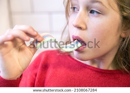Close up, little girl eating gummy candy.