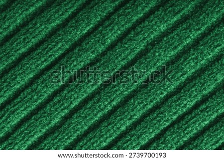 Close up, macro of green colored knitted fabric with diagonal relief ribbed pattern and soft wool texture. Detailed textile surface, knitwear background, fashion, backdrop, design element.