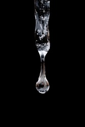 Close Up, Macro Of Water Drop Forming And Falling From Single Isolated Icicle In Front Of Dark Background