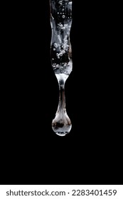close up, macro of water drop forming and falling from single isolated icicle in front of dark background - Shutterstock ID 2283401459