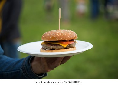 Close up, man holding plate with burger at street food festival, take away food