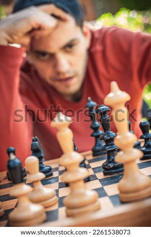 Close up. Man playing chess, thinking about next move, spring day, outside.