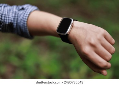 Close up, man using smart watch series, setting up his smart watch in the forest, goal achievement, sport and fitness concept outdoors in nature.