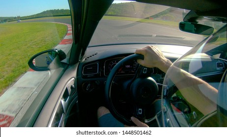 CLOSE UP: Man Wearing A Helmet Races His Fast Car Along The Fun Racetrack. Unrecognizable Adrenaline Seeking Male Race Car Driver Having Fun By Driving His Awesome Sportscar Along A Closed Track.